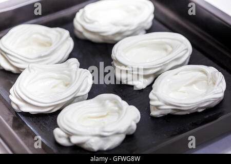 Raw meringues on baking sheet Stock Photo