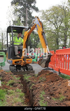 A workman excavates a trench for new fibre-optic cables for high speed broadband in a rural part of Kent, UK Stock Photo