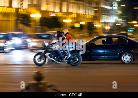 Man and woman on motorcycle at night in city Stock Photo