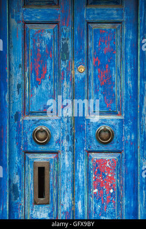 Old rustic blue red painted wooden house doors. Cotswolds, England Stock Photo