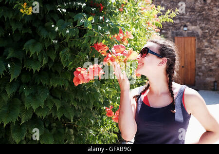 Teenage girl smelling beautiful flowers at Beynac-et-Cazenac a beautiful medieval village on the River Dordogne France Stock Photo