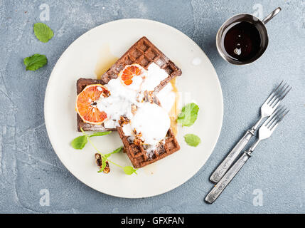 Belgian soft waffles with blood orange, cream, marple syrup and mint  on white plates Stock Photo