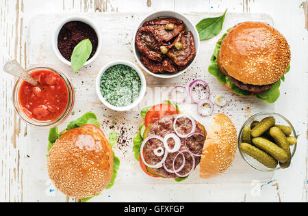 Homemade beef burgers with onion, pickles, vegetables, sun-dried tomatoes, sauce Stock Photo