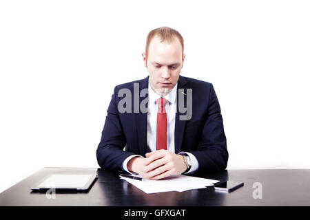 Finnish businessman in red tie at the table thought before signing the contract. Isolated on white background Stock Photo