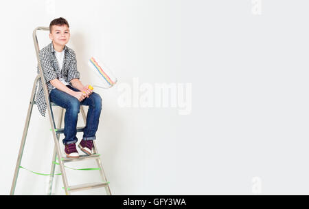 Boy with roller on ladder Stock Photo