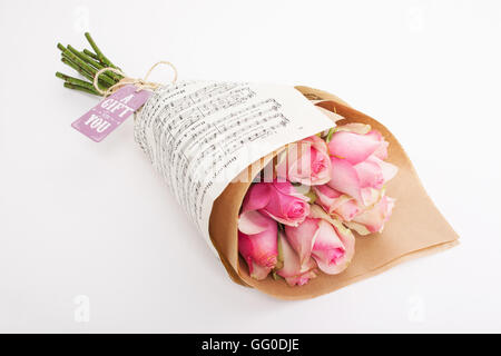 Gift bouquet of pink roses wrapped in music paper with a gift card and tie Stock Photo