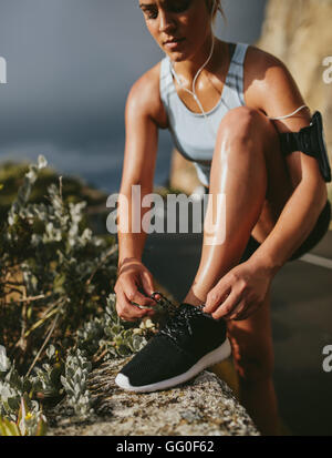 Female lacing sport shoes. fitness woman tying shoe lace before running outdoors, workout wellness concept. Stock Photo