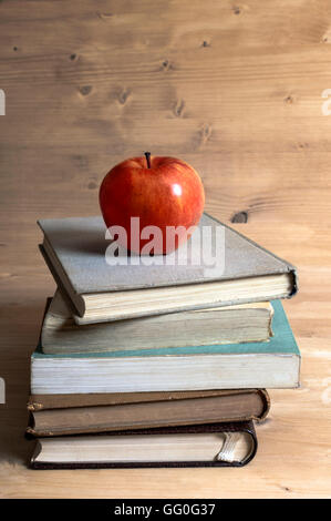 Stack of books and red apple on wooden table. Selective focus. Stock Photo