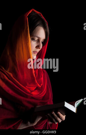 Woman reading a Bible in the night. Isolated on a black background Stock Photo
