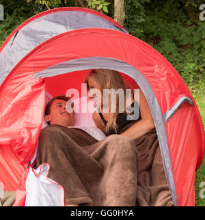 Young couple on holiday sharing a small tent Stock Photo