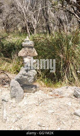 Conical pile of rocks, cairns, in a wetland nature setting at Lake Coogee with native flora in Western Australia. Stock Photo