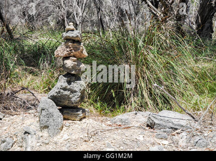 Conical pile of rocks, cairns, in a wetland nature setting at Lake Coogee with native flora in Western Australia. Stock Photo