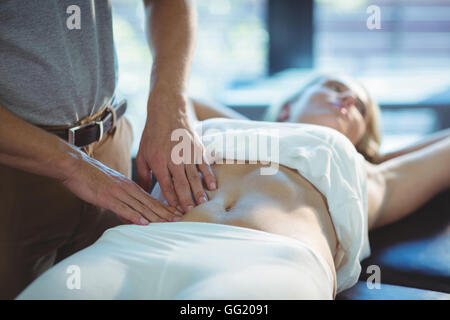 Physiotherapist giving stomach massage to a woman Stock Photo