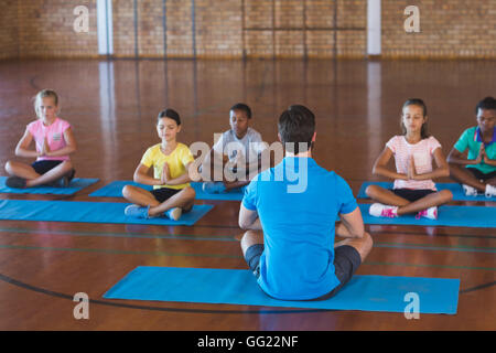 School kids and teacher meditating during yoga class Stock Photo