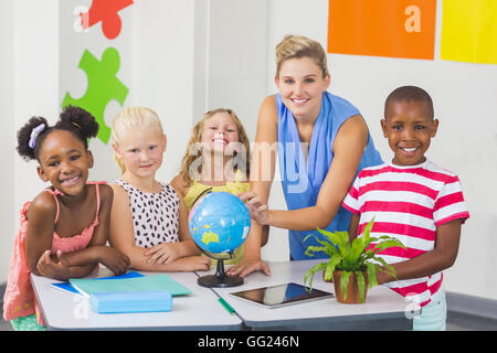 Teacher discussing globe with kids Stock Photo