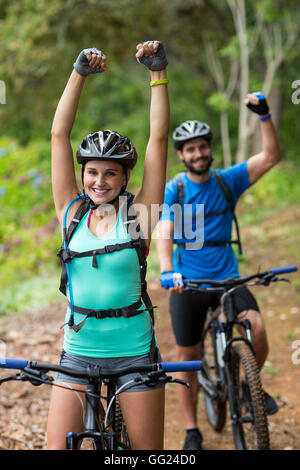 Athletic couple standing with mountain bike in forest Stock Photo