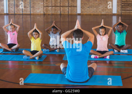 School kids and teacher meditating during yoga class Stock Photo