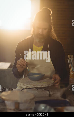 Attentive male potter painting on bowl Stock Photo - Alamy