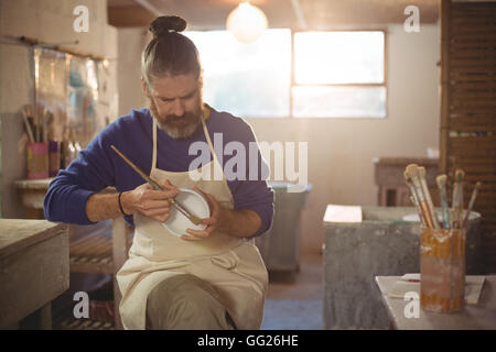 Male potter painting on bowl Stock Photo - Alamy