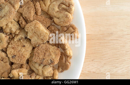 Top close view of a plate with broken chocolate chip animal crackers on a white background. Stock Photo
