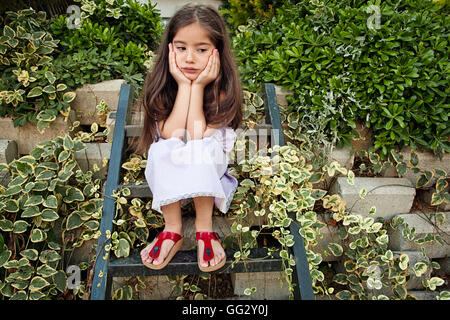 Sad little girl sitting on steps and thinking Stock Photo