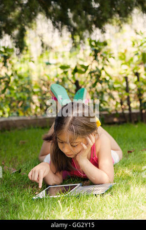Girl lying on grass,using digital tablet Stock Photo