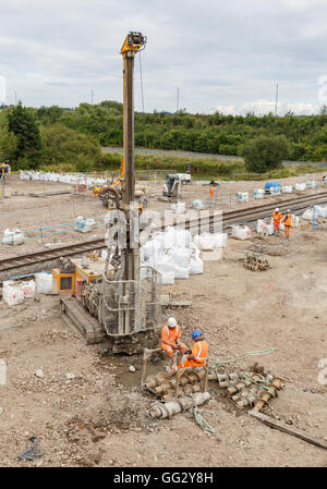 Construction workers sitting next to a pile drilling machine on a railway side site. In Ilkeston, Derbyshire, England. Stock Photo