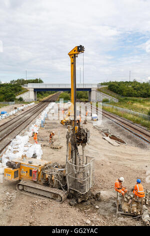 Construction workers, and pile drilling machine, on site next to a section of railway track. In Ilkeston, Derbyshire, England. O Stock Photo