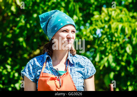 mature funny woman farmer wearing headscarf apron hat in garden Stock Photo