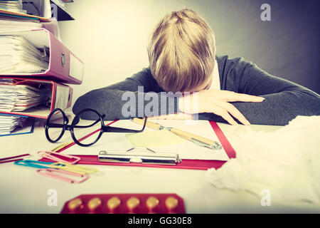 Health concept at business work. Tired overworked young businesswoman secretary manager. Sick ill young female sleeping at workplace. Stock Photo