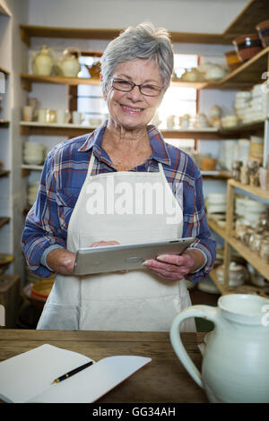 Happy female potter using digital tablet Stock Photo