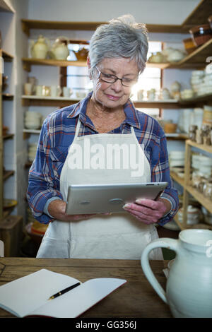 Attentive female potter using digital tablet Stock Photo
