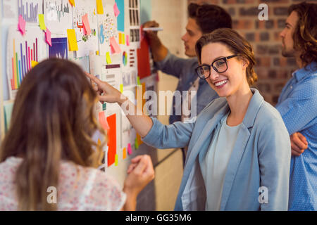 Business executives looking at sticky notes on whiteboard Stock Photo