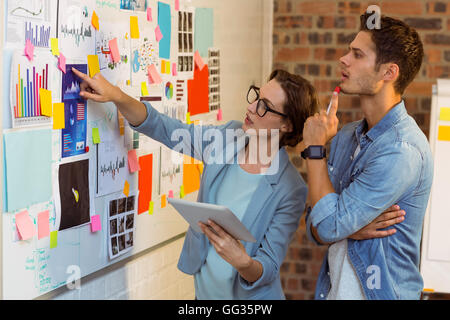 Business executives looking at sticky notes and graph on white board Stock Photo