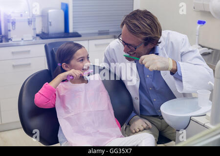 Smiling dentist and patient brushing their teeth Stock Photo