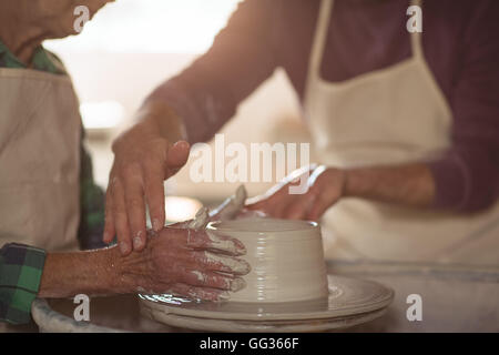 Mid-section of male potter assisting female potter Stock Photo