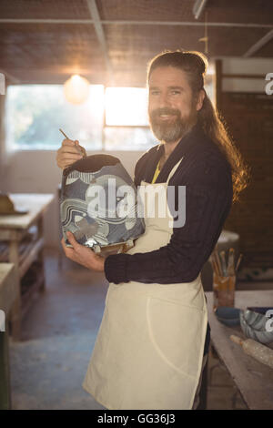 Smiling male potter painting on bowl Stock Photo - Alamy