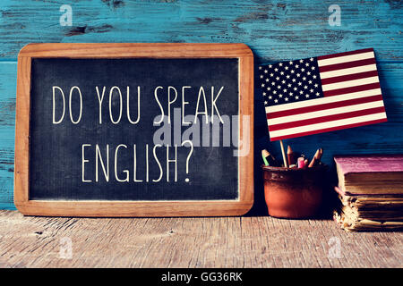 a chalkboard with the question do you speak English? written in it, a pot with pencils and the flag of the United States, on a w Stock Photo