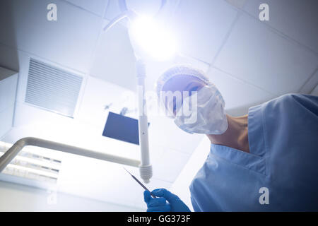 Dental assistant in surgical mask holding dental tools Stock Photo