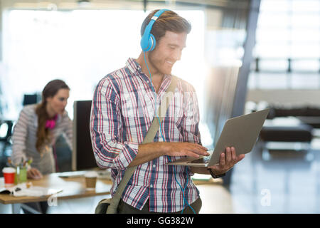 Smiling man with headphone using laptop Stock Photo