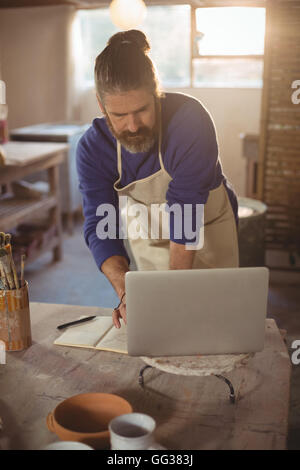 Male potter working on laptop Stock Photo