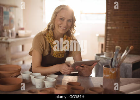 Beautiful female potter using digital tablet Stock Photo