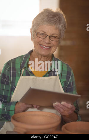 Portrait of female potter using digital tablet Stock Photo