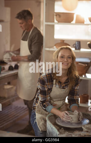 Smiling female potter making pot in pottery workshop Stock Photo