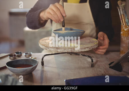 Male potter painting bowl in pottery workshop Stock Photo - Alamy