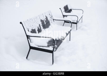 Two outdoor metal benches covered with snow in winter park. Turku, Finland Stock Photo