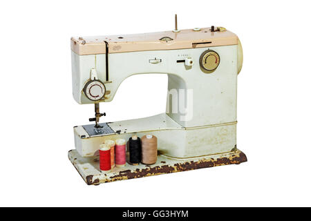 Old rusty vintage sewing machine with cotton reels, grungy scissors and tape measure on white background Stock Photo