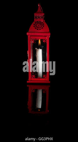 red candle lamp with white candle on black background on his own reflection Stock Photo