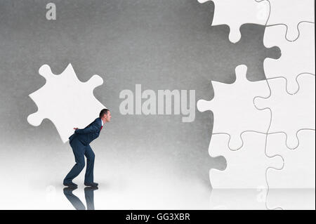 business puzzle concept businessman working to complete a jigsaw Stock Photo