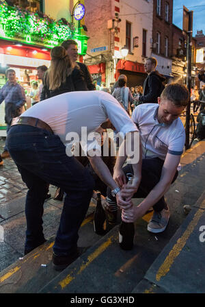 youths trying to open bottle of alcohol on street at night in Temple Bar, Dublin, Ireland Stock Photo
